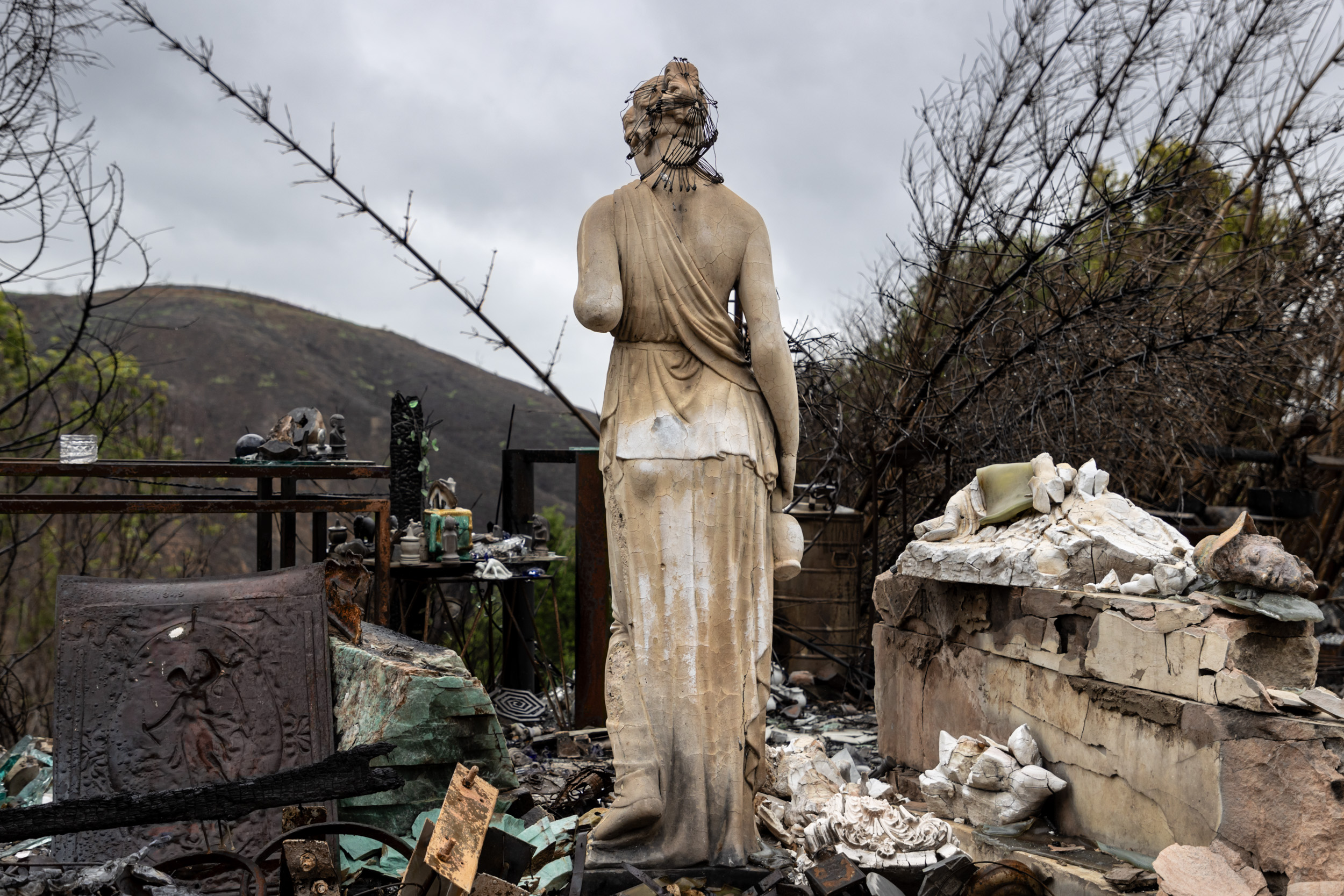 Garden statue of a woman overlooking the wreckage of the Palisades Fire